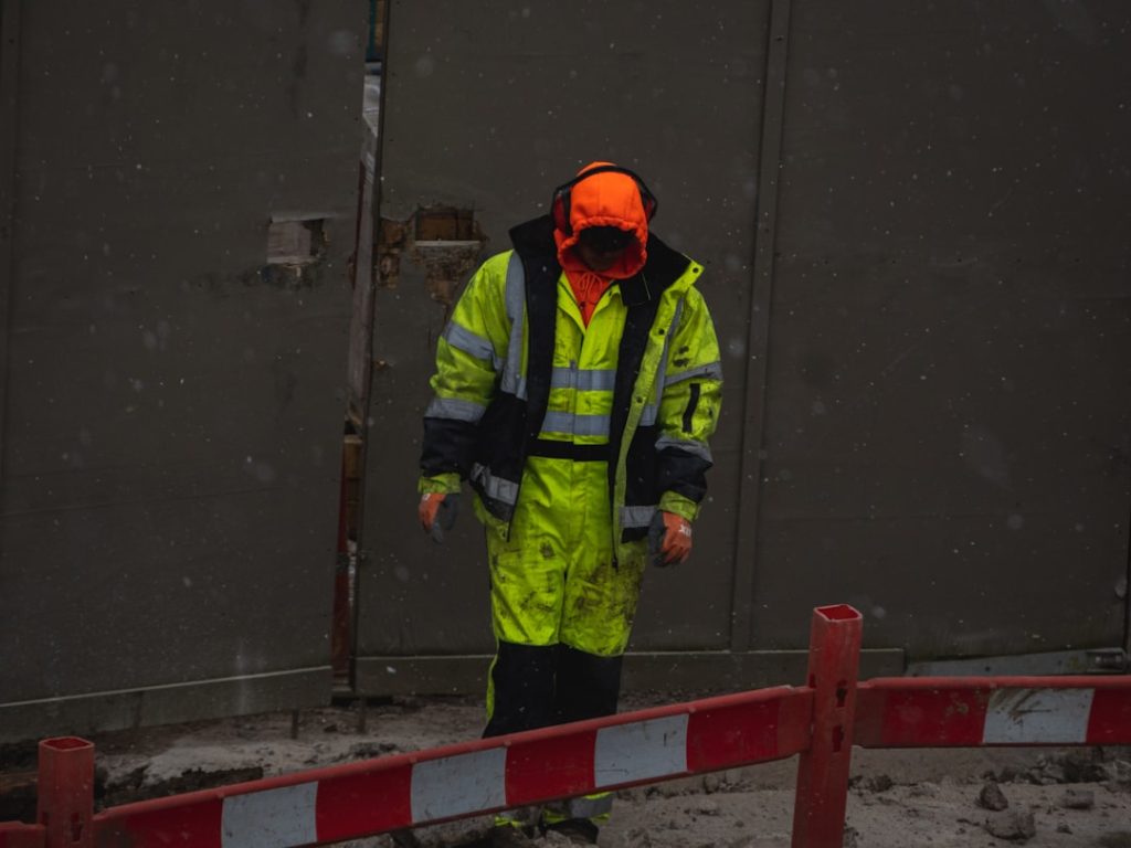man-in-green-jacket-and-orange-helmet-standing-on-gray-concrete-floor-5yijatx-yec