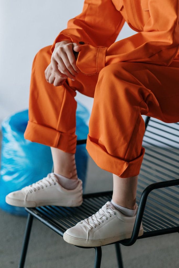 Close-up of a person in an orange uniform sitting on a black chair indoors.