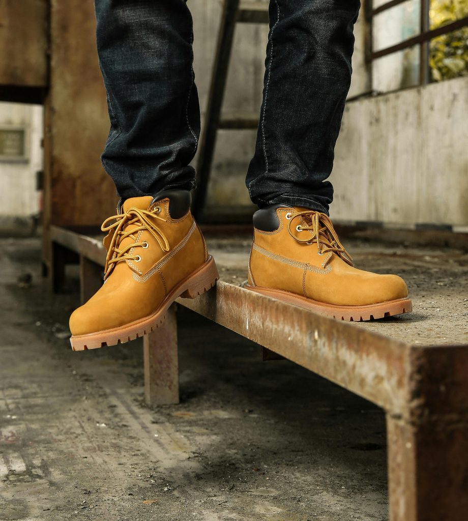 Fashionable tan boots on a rustic metal beam indoors. Urban style captured in a vertical shot.